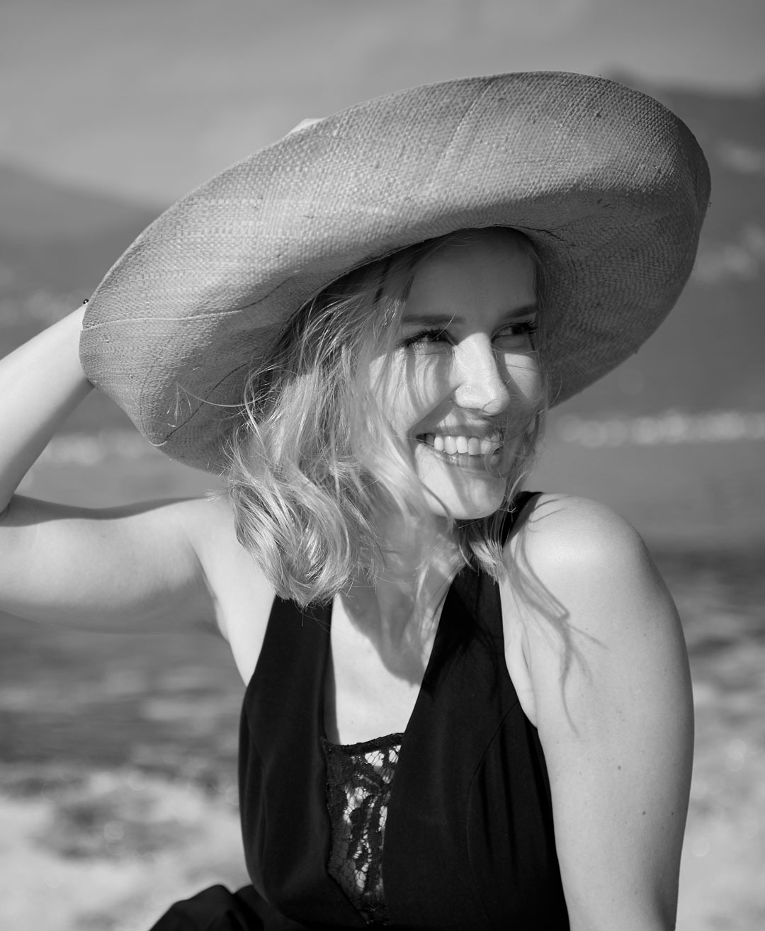 Donna con ampio cappello fotografata con paesaggio sullo sfondo durante un tour in barca sul Lago di Como